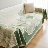 Floral patterned green and beige blanket draped over a sofa in a living room.